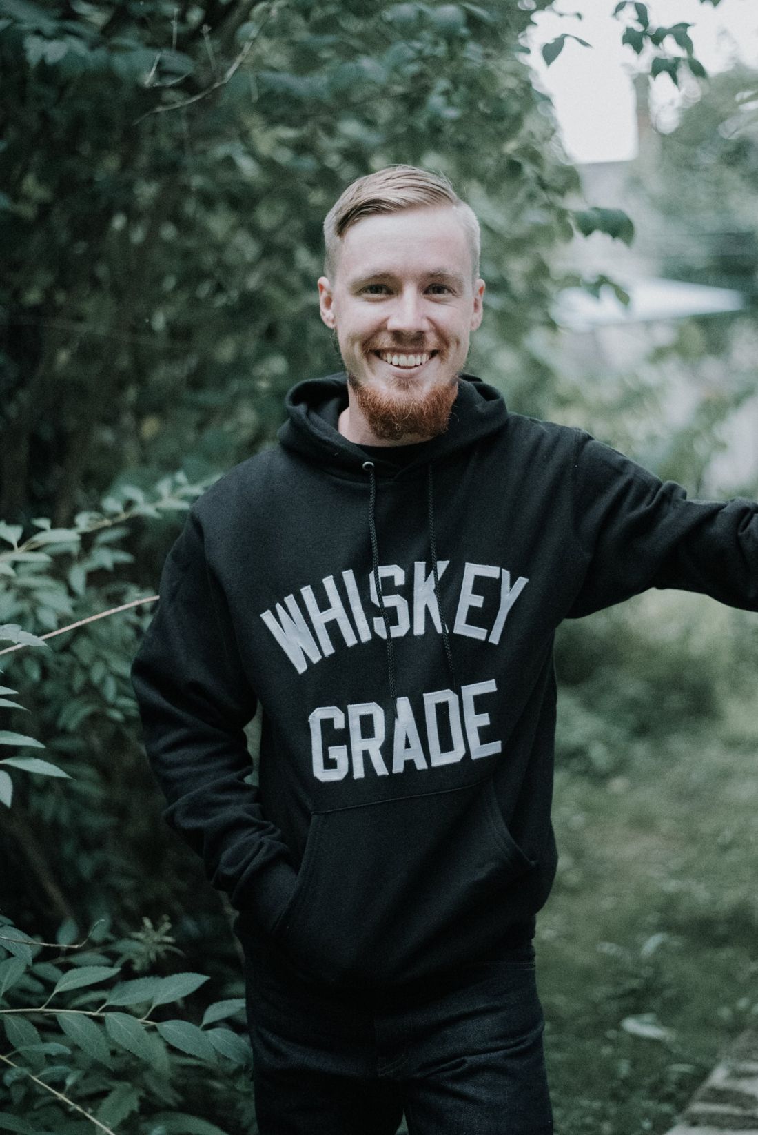 Josh Witt smiling in a garden, wearing a black hoodie